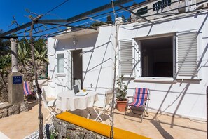 Ein weißes Gebäude mit einer Terrasse, einem Tisch mit einem Laptop und zwei Stühlen.