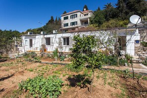 Ein zweistöckiges Gebäude mit einem Garten im Vordergrund.