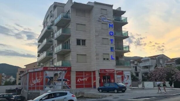 Ett hotell med flera våningar och balkonger, en reklam för Coca-Cola och en parkerad bil.