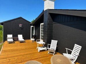 A wooden deck with white outdoor furniture, a basketball hoop, and a black building with a white door. - Panoramic sea View Direct Sandy Beach Skagen South (Aalbaek)
