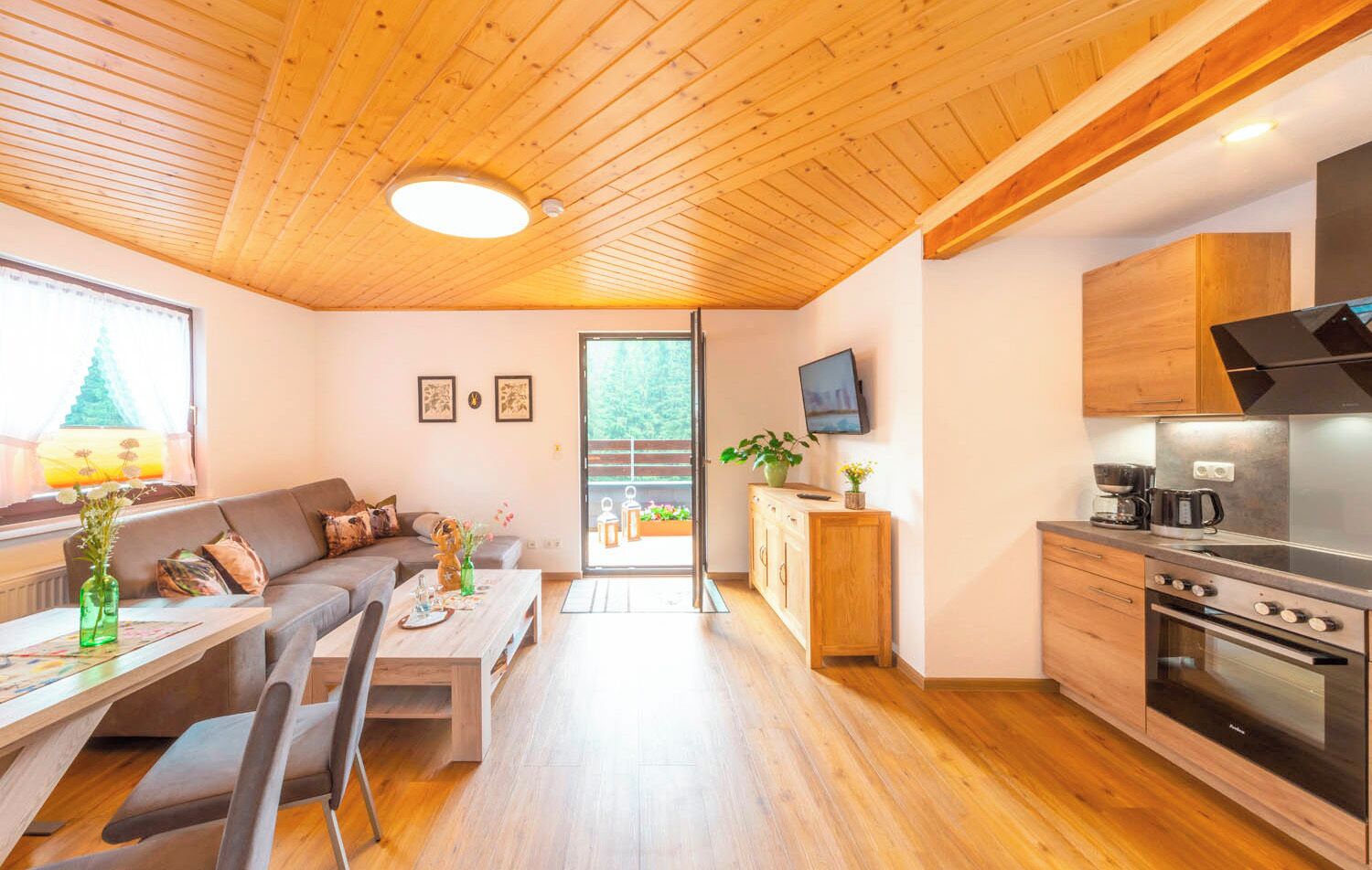 Una cocina moderna con horno empotrado y comedor con mesa y sillas de madera.