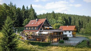 Eine große, zweistöckige Chalet mit rotem Dach, umgeben von dichtem Wald.