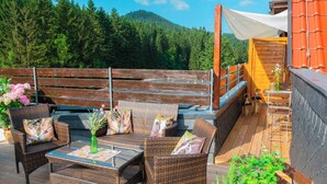Eine Terrassenausstattung mit Korbmöbeln, einem Tisch und einer Bank.