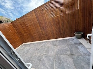 A patio with grey stone tiles, a wooden fence, and a potted plant. - Stunning 4BR Brighton House - Near Beach & Lanes (Brighton)