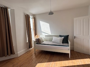 Una habitació amb un llit, una finestra i una porta.