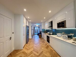 A modern kitchen with white cabinetry, a microwave, and a dishwasher. - Stunning 4BR Brighton House - Near Beach & Lanes (Brighton)
