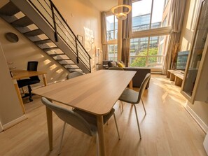 A modern interior with a dining area, staircase, and large windows. - Urban Loft Nook • City Views• Free Parking (Vancouver)