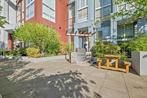 A courtyard with a barbecue grill, a wooden table, and a pergola. - Urban Loft Nook • City Views (Vancouver)