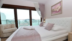 Una camera da letto con un letto grande, una sedia, un comodino e un quadro appeso al muro.
