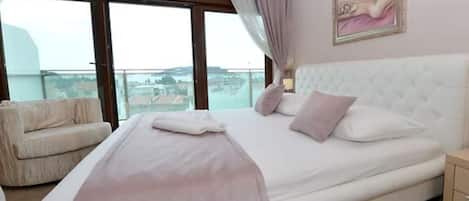 A bedroom with a large bed, a chair, a nightstand, and a painting on the wall.