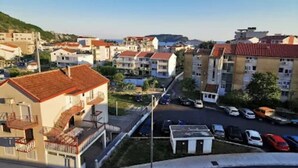 Ein Wohngebiet mit mehrstöckigen Gebäuden, eine Straße mit parkenden Autos und einem klaren Himmel.