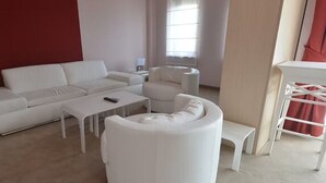 Ein modernes Wohnzimmer mit einem weißen Sofa, einem weißen Couchtisch, einem weißen Sessel und einer weißen Hocker.