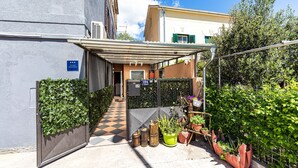 Un edificio residencial con un porche cubierto, un camino a cuadros y plantas en macetas.