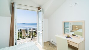 A hotel room with a balcony, a bed, a desk, and a mirror. - Villa Samba - Luxury One-bedroom Apartment With Balcony and Sea View (Zupa dubrovacka)