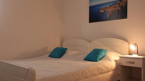 A single-bed room with a headboard, two pillows, a bedside table with a lamp, and a painting on the wall. - Villa Nika-five Bedroom Villa With Pool (Zupa dubrovacka)