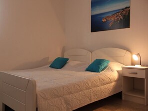 A single-bed room with a headboard, two pillows, a bedside table with a lamp, and a painting on the wall. - Villa Nika-five Bedroom Villa With Pool (Zupa dubrovacka)