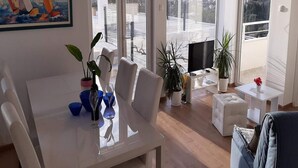 A modern living room with a dining area, large windows, and a painting of sailboats. - Villa Nika-five Bedroom Villa With Pool (Zupa dubrovacka)