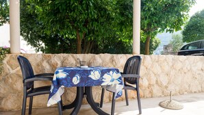 An outdoor table set with a tablecloth, two chairs, and a stone wall backdrop. - Apartments Radic - Studio Apartment - Kneza Domagoja Street - BR 1 (Dubrovnik)