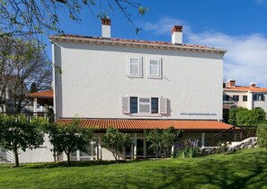 Ein zweistöckiges Gebäude mit weißer Fassade, rotem Ziegeldach und Fensterläden.