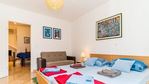 A hotel room with a bed, a sofa, a dining area, and artwork on the walls. - Apartments Casa Vanna - One Bedroom Apartment (Dubrovnik)
