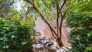 An outdoor seating area with stone flooring, metal chairs, and a table. - Apartments Casa Vanna - One Bedroom Apartment (Dubrovnik)