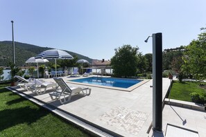 A swimming pool with lounge chairs and umbrellas, surrounded by greenery and a mountain in the background. - Villa Celenca - Superior Two Bedroom Apartment With Terrace and Sea View - A5 (Dubrovnik)