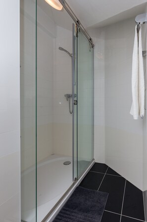 A glass-enclosed shower with a white tiled wall and a black floor. - Villa Celenca - Superior Two Bedroom Apartment With Terrace and Sea View - A5 (Dubrovnik)