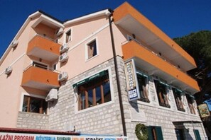 A multi-story building with balconies, a ground-level shop, and a sign indicating a restaurant. - Fiammanti Hotel Montenegro-Standard Triple Room (Herceg Novi)