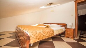 A bedroom with a checkered floor, a wooden bed with a patterned bedspread, a nightstand, and a wardrobe. - Fiammanti Hotel Montenegro-One Bedroom Apartment (Herceg Novi)