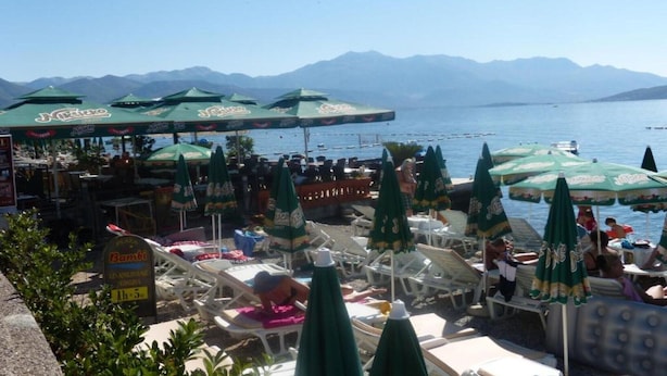 A seaside restaurant with outdoor seating and umbrellas, overlooking a body of water and mountains. - Fiammanti Hotel Montenegro-One Bedroom Apartment (Herceg Novi)