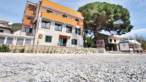 A multi-story building with a stone facade, a large tree in front, and a gravel ground. - Fiammanti Hotel Montenegro-One Bedroom Apartment (Herceg Novi)