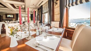 A dining area with tables set for a meal, featuring candles, cutlery, and glasses. - Fiammanti Hotel Montenegro-One Bedroom Apartment (Herceg Novi)