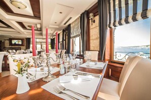 A dining area with tables set for a meal, featuring candles, cutlery, and glasses. - Fiammanti Hotel Montenegro-One Bedroom Apartment (Herceg Novi)