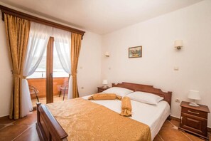 A hotel room with a bed, a chair, a nightstand, a lamp, and a window with curtains.