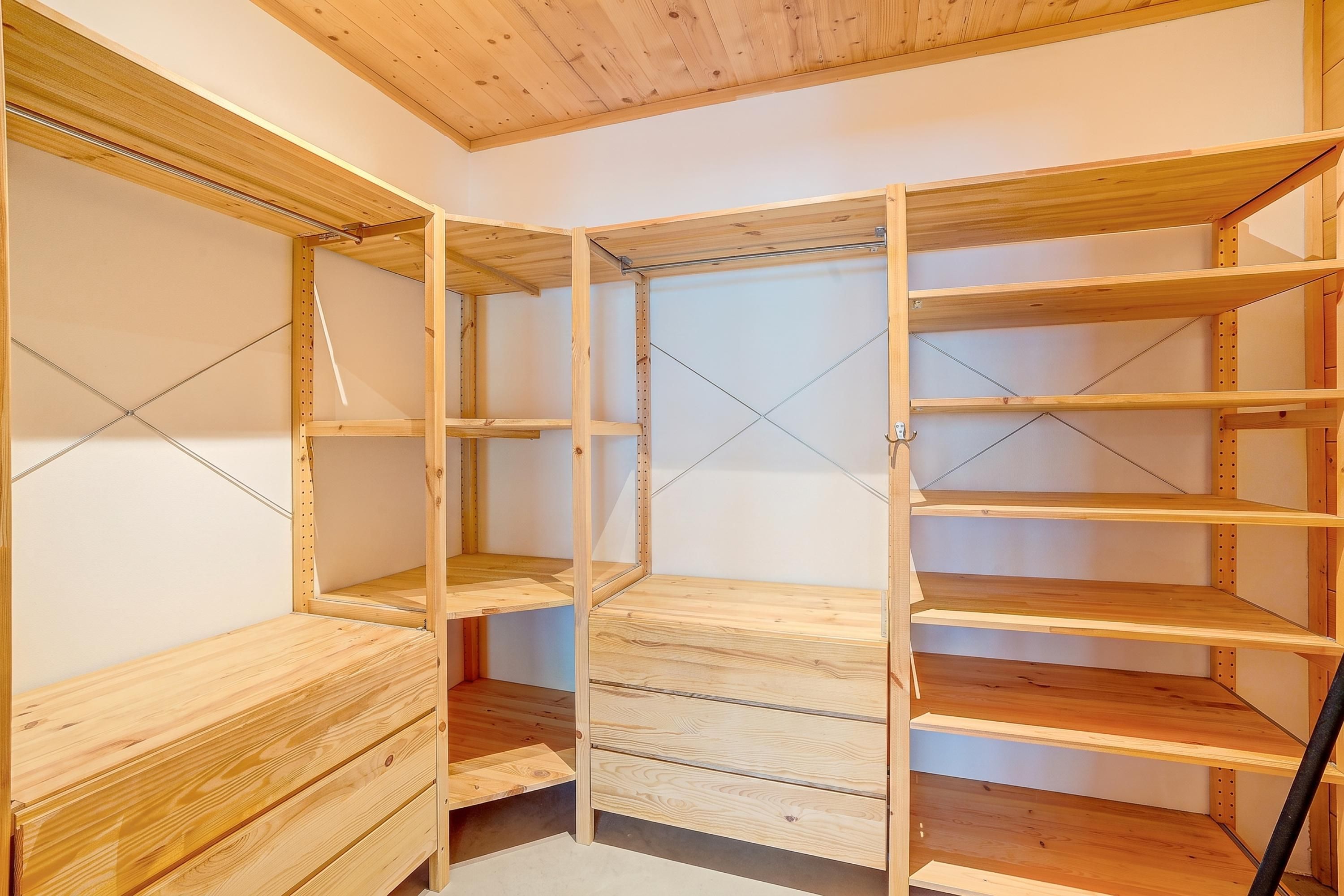 A walk-in closet with wooden shelving and drawers.