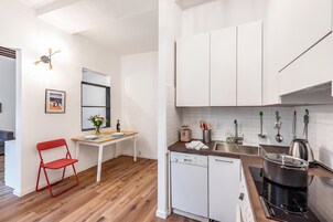 Una cocina compacta con armarios blancos, lavavajillas y estufa.