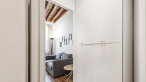 A modern interior with a grey sofa, a small round table, and a white wardrobe. - Old Town Living in Historic Center & A/C (Genoa)