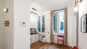 A compact kitchen with a dining area, a red chair, and a window with curtains. - Old Town Living in Historic Center & A/C (Genoa)
