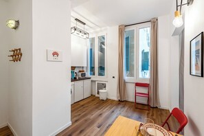 Eine kleine Küche mit Essbereich, einem roten Stuhl und einem Fenster mit Vorhängen.