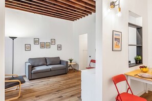 A modern living room with a grey sofa, wooden flooring, and a ceiling with exposed beams. - Old Town Living in Historic Center & A/C (Genoa)