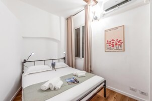 Una habitación de hotel con una cama, un ventanal, un aire acondicionado de pared y un cuadro enmarcado.