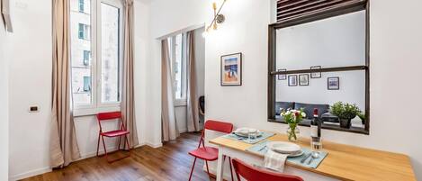 Un comedor moderno con una mesa de madera, sillas rojas y una ventana con cortinas.