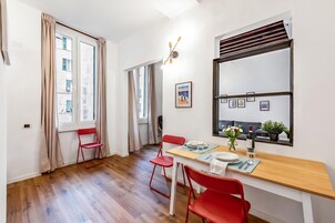 Un comedor moderno con una mesa de madera, sillas rojas y una ventana con cortinas.
