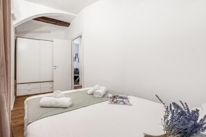 Habitación de hotel con cama, una revista, una planta y vistas al baño.