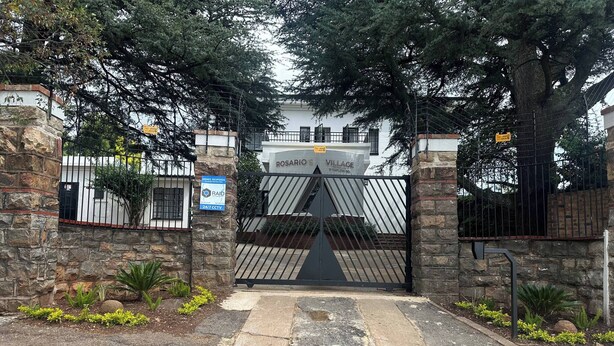 A gated entrance with a stone wall, a metal gate, and a sign indicating armed response and 24/7 CCTV. - Room-single Self-contained Rooms (Johannesburg)