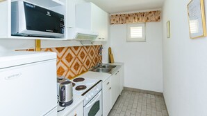 Una cocina compacta equipada con microondas, hervidor, estufa y un ventanal.