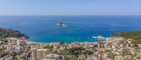 Une ville côtière avec des bâtiments, une mer d’un bleu limpide et une petite île.