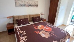 Ein Schlafzimmer mit einem Bett, zwei Nachttischen, einem Holzschrank und einem an der Wand hängenden Kunstwerk.