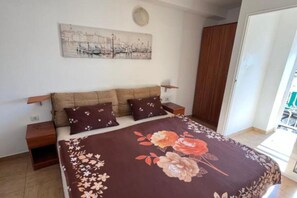 Ein Schlafzimmer mit einem Bett, zwei Nachttischen, einem Holzschrank und einem an der Wand hängenden Kunstwerk.