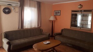 Ein Wohnzimmer mit zwei Sofas, einem Couchtisch, einer Lampe und einer Wand-Klimaanlage.